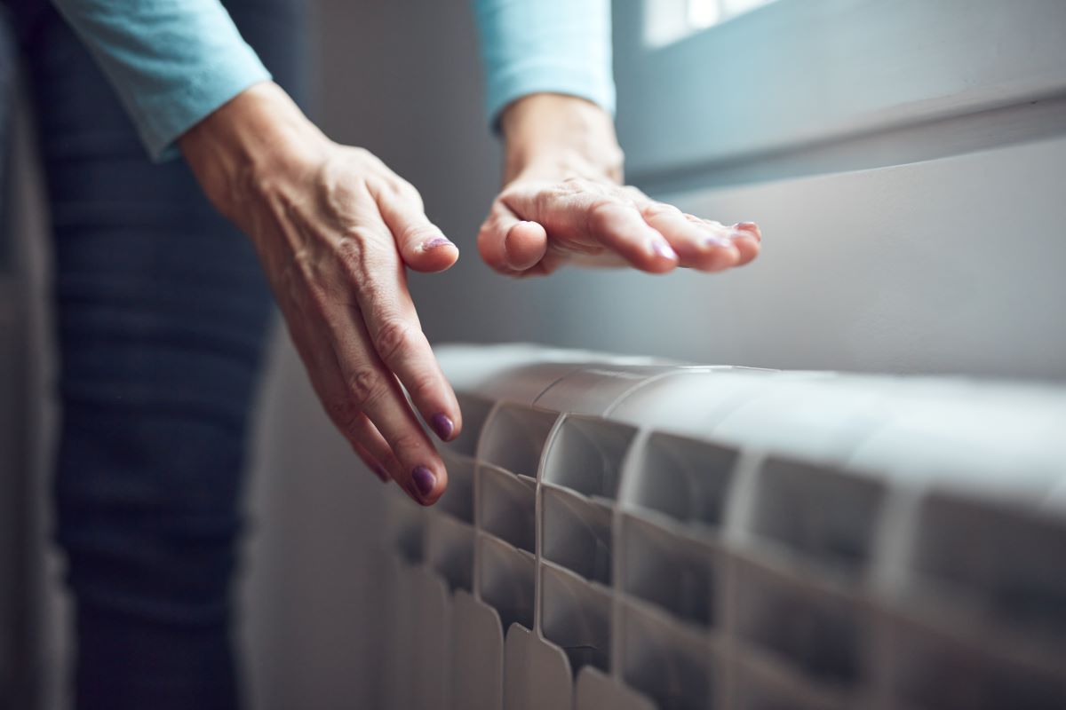 Womans hands over radiator - heating
